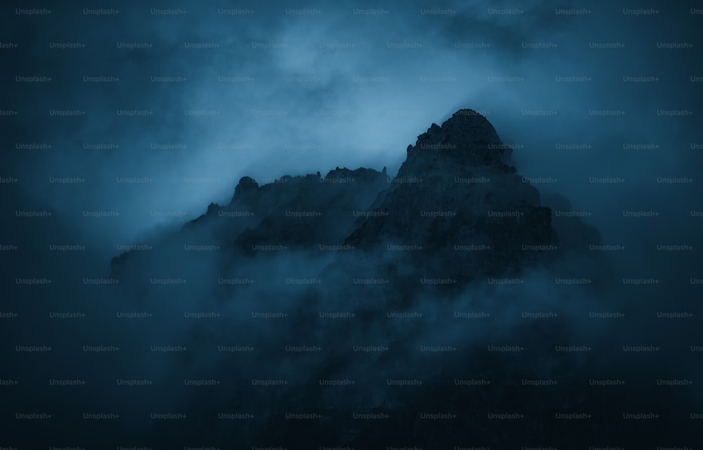 a very tall mountain in the middle of a cloudy sky