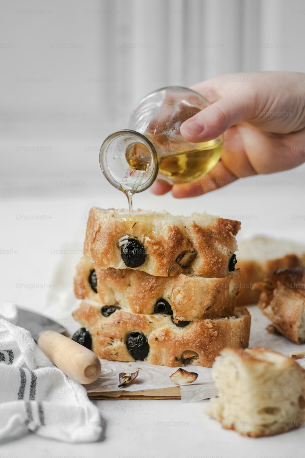 a person pouring olives into a loaf of bread