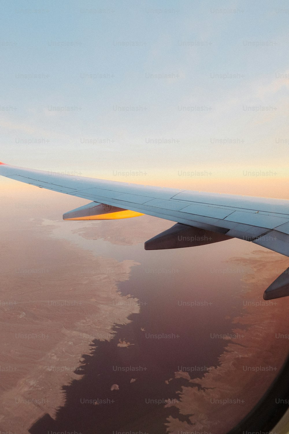 a view of the wing of an airplane as it flies over a body of water