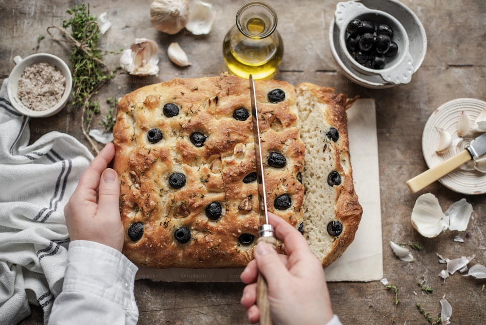 a person cutting a blueberry bread on a cutting board