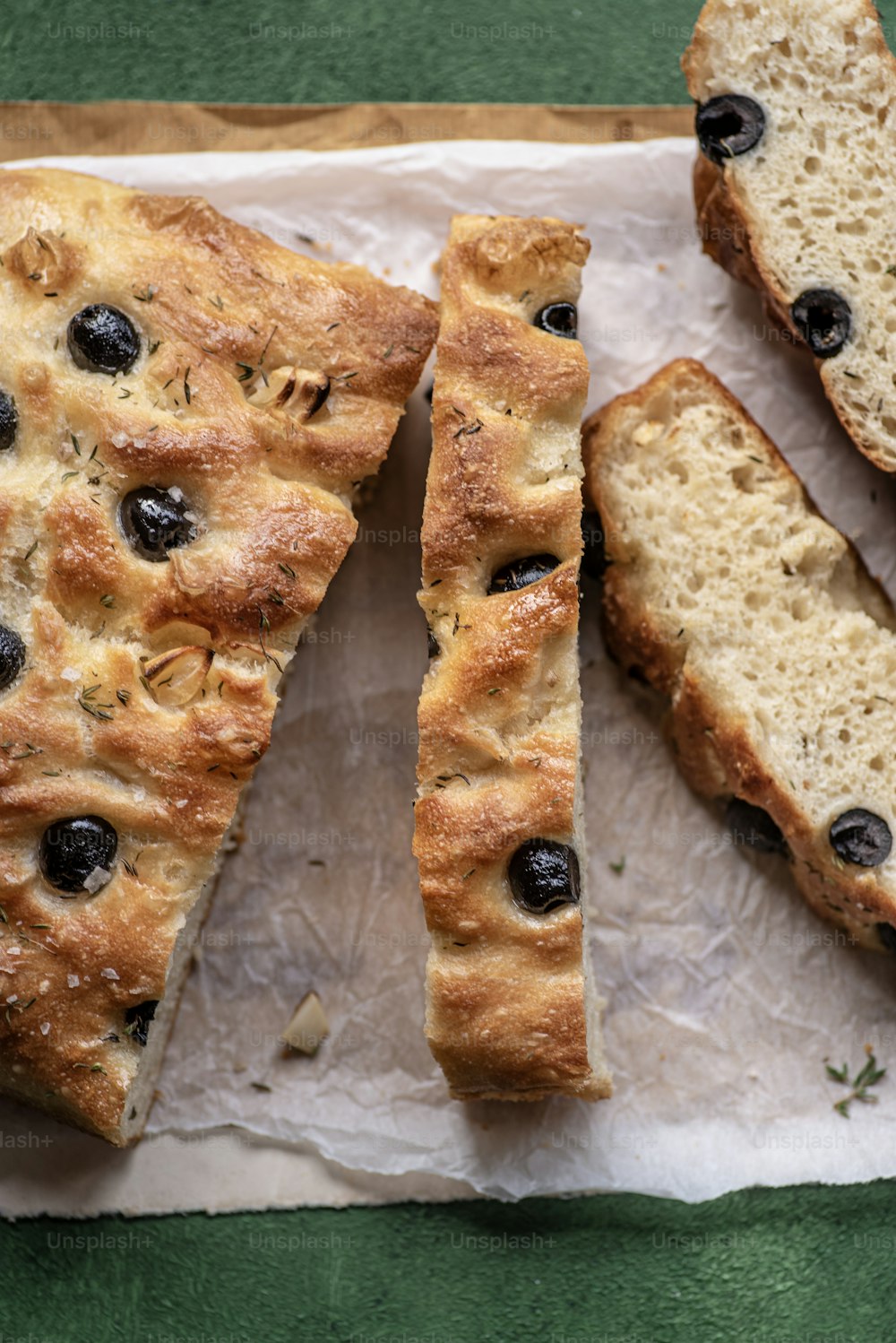 a loaf of bread with olives on a piece of parchment paper