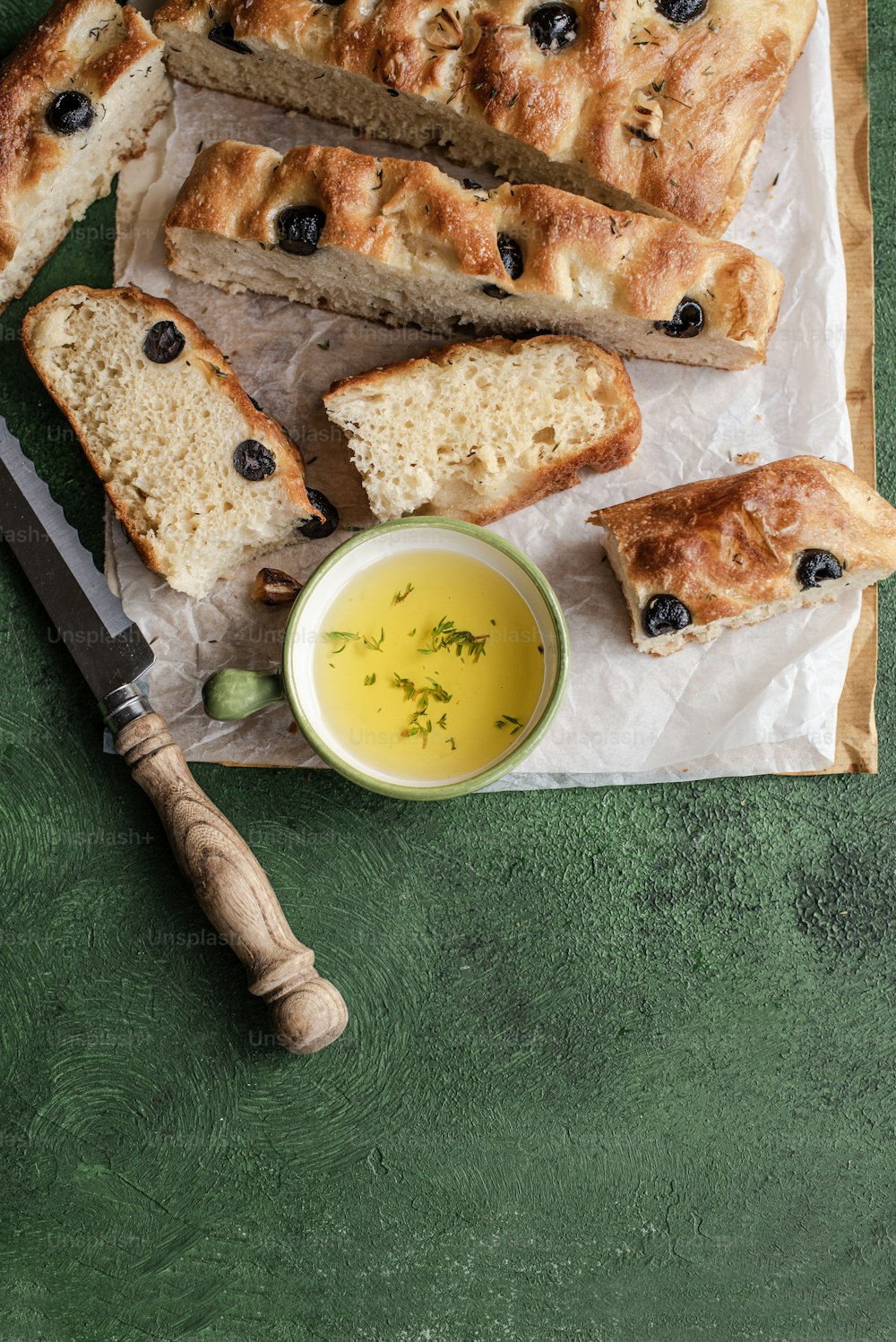 a loaf of bread with olives and a bowl of olive oil