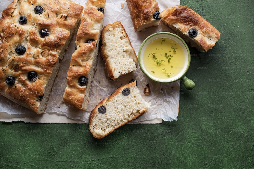 a loaf of bread with olives and a cup of olive oil