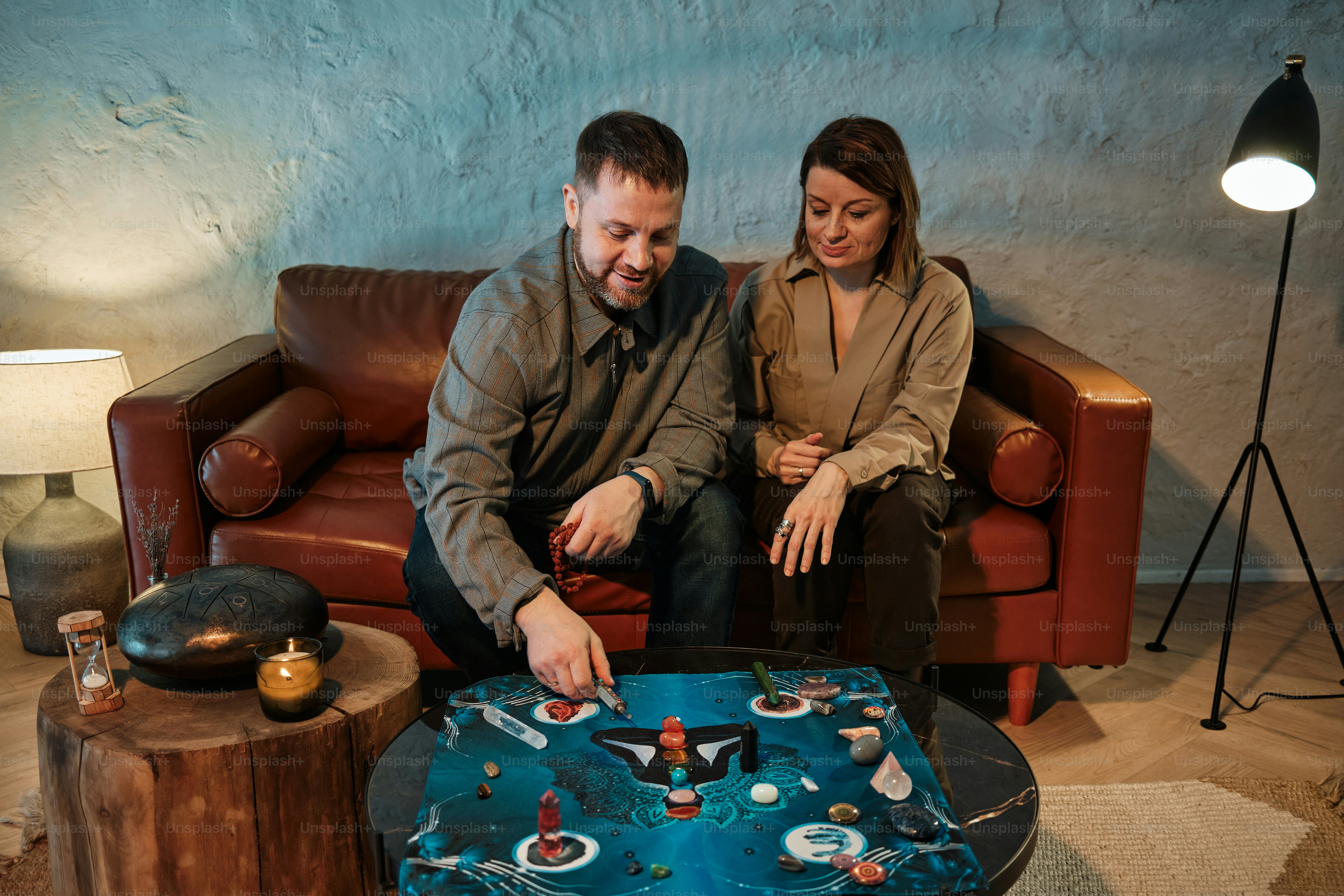 um homem e uma mulher sentados em um sofá cortando um bolo