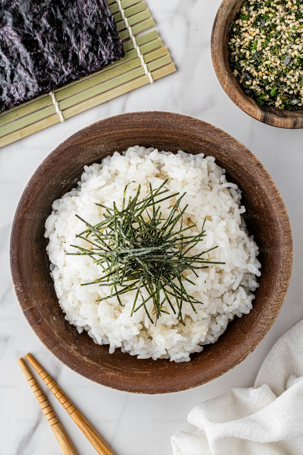un bol en bois rempli de riz à côté de baguettes