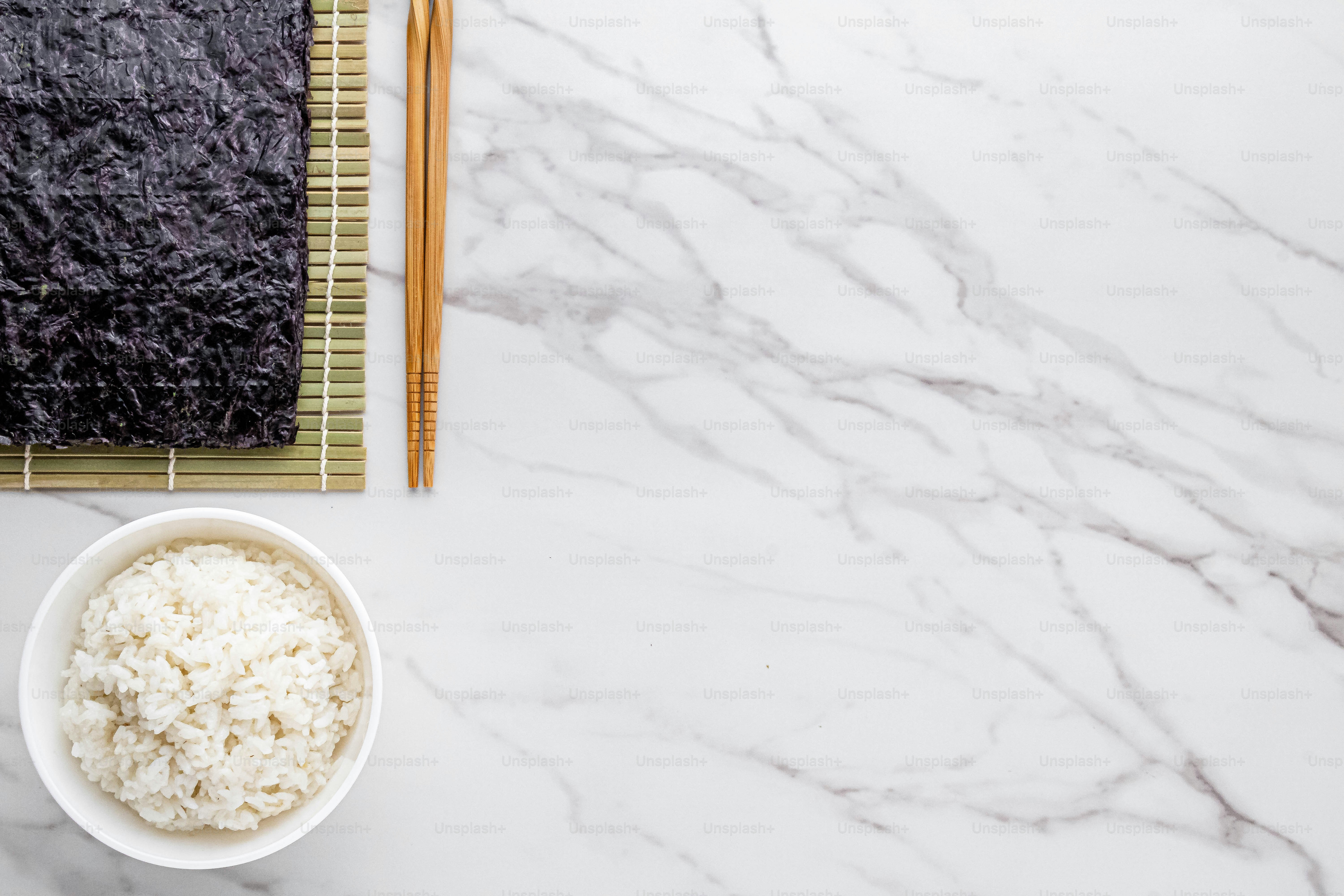 eine Schüssel mit Reis und Essstäbchen auf einem Tisch