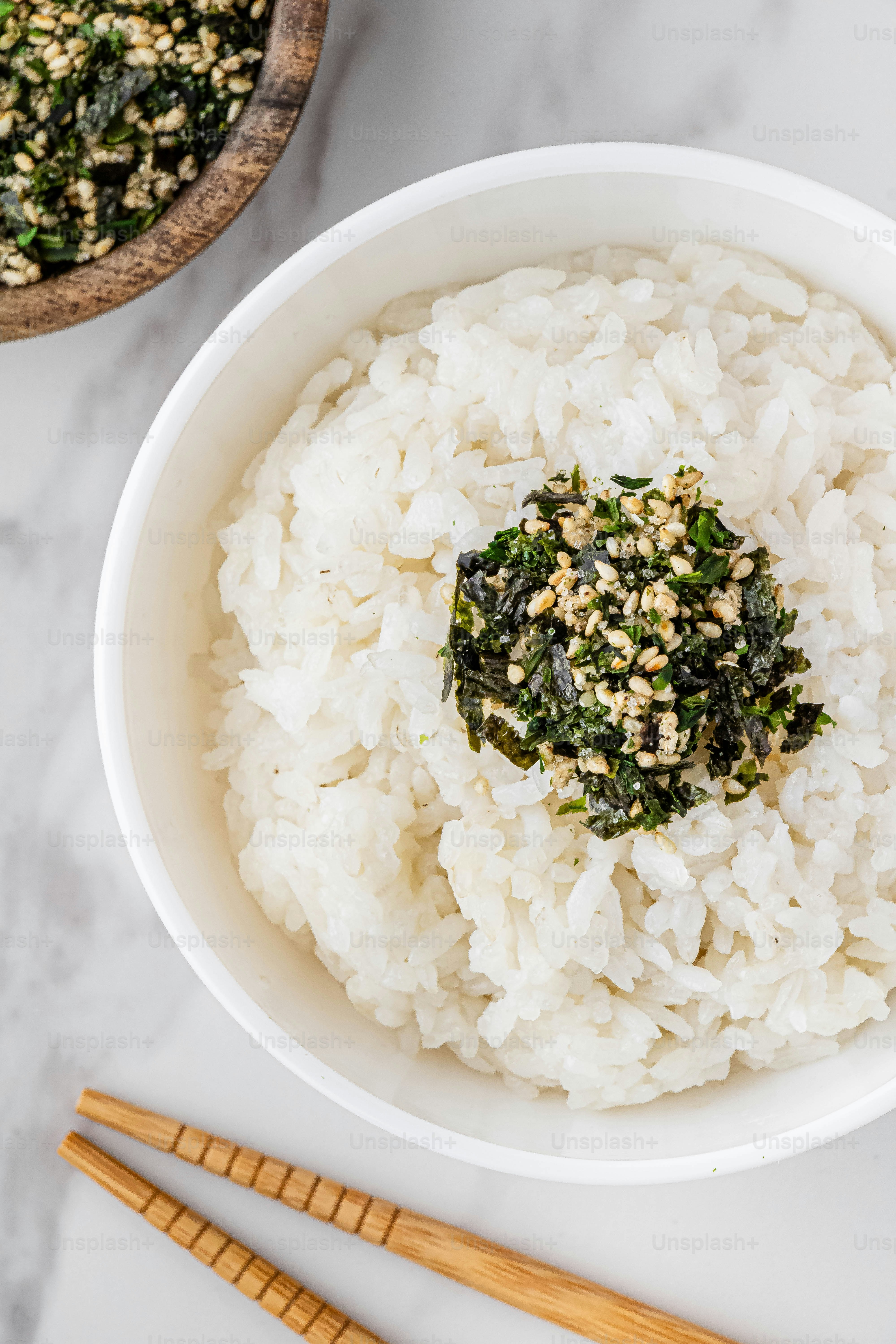 a bowl of white rice and chopsticks on a table