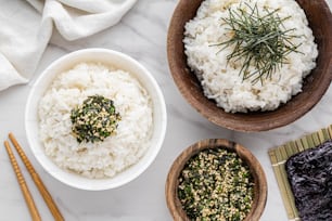 Tres cuencos de arroz blanco y palillos sobre una mesa