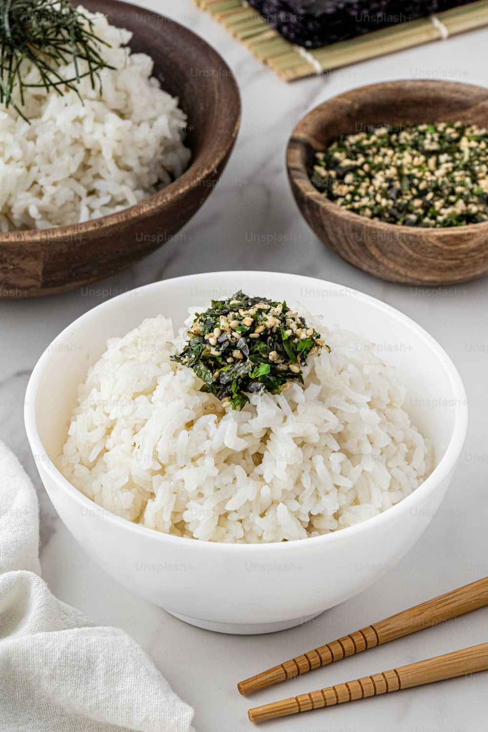 a bowl of white rice and two bowls of rice with chopsticks