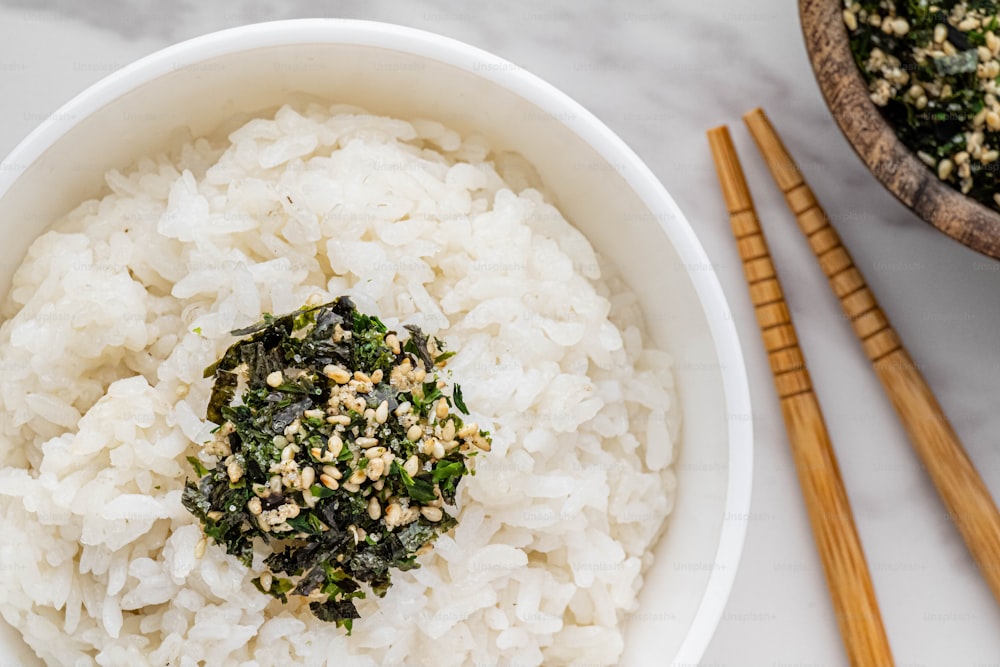 uma tigela de arroz e pauzinhos sobre uma mesa