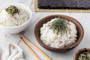 eine Schüssel Reis und zwei Schüsseln Reis mit Stäbchen