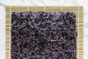 Un primer plano de una alfombra púrpura sobre una estera de bambú
