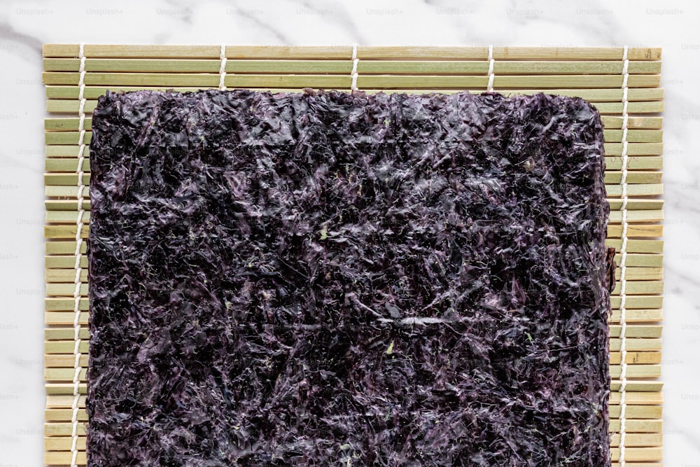 Un primer plano de una alfombra púrpura sobre una estera de bambú