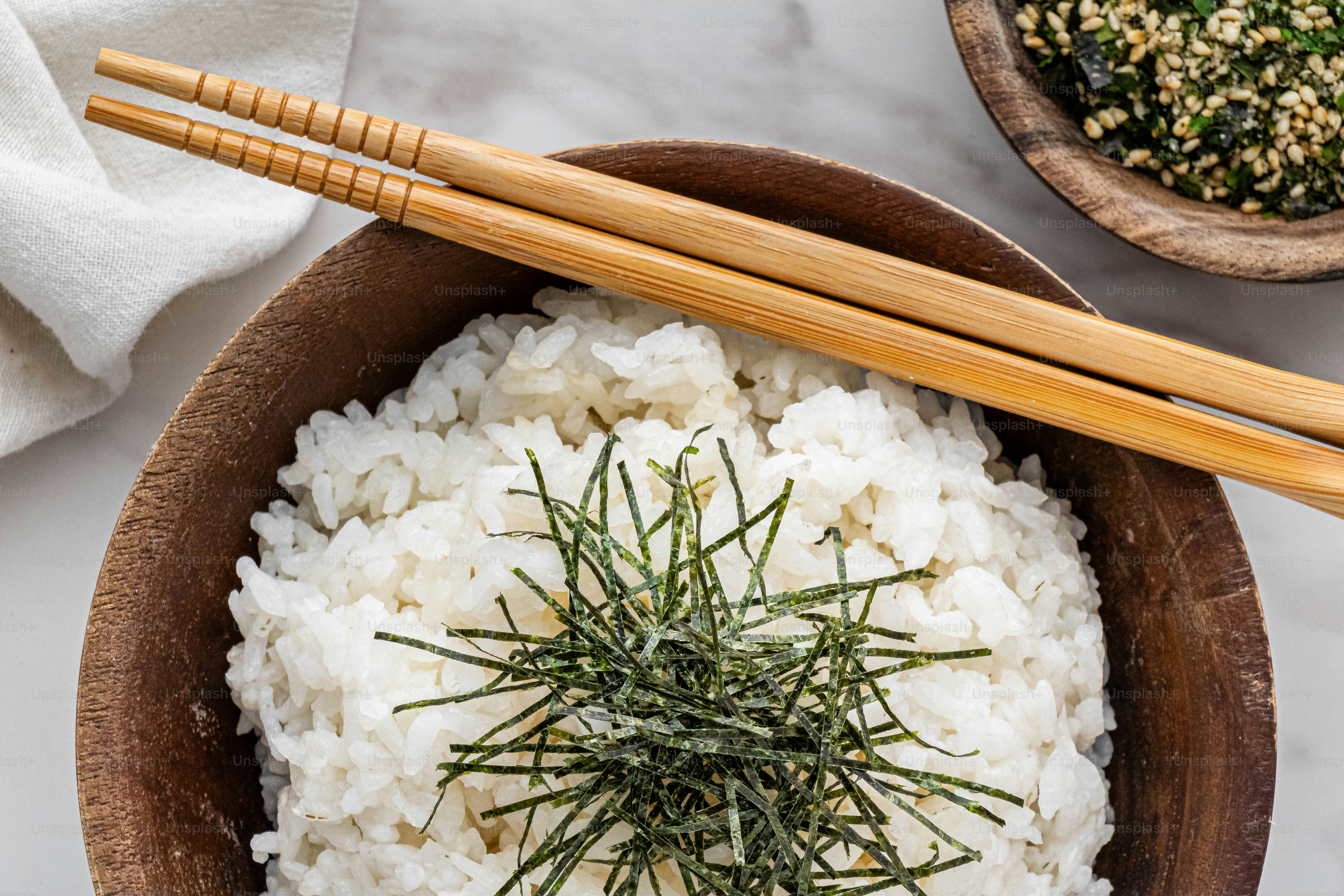 eine Holzschüssel gefüllt mit Reis und ein Paar Essstäbchen