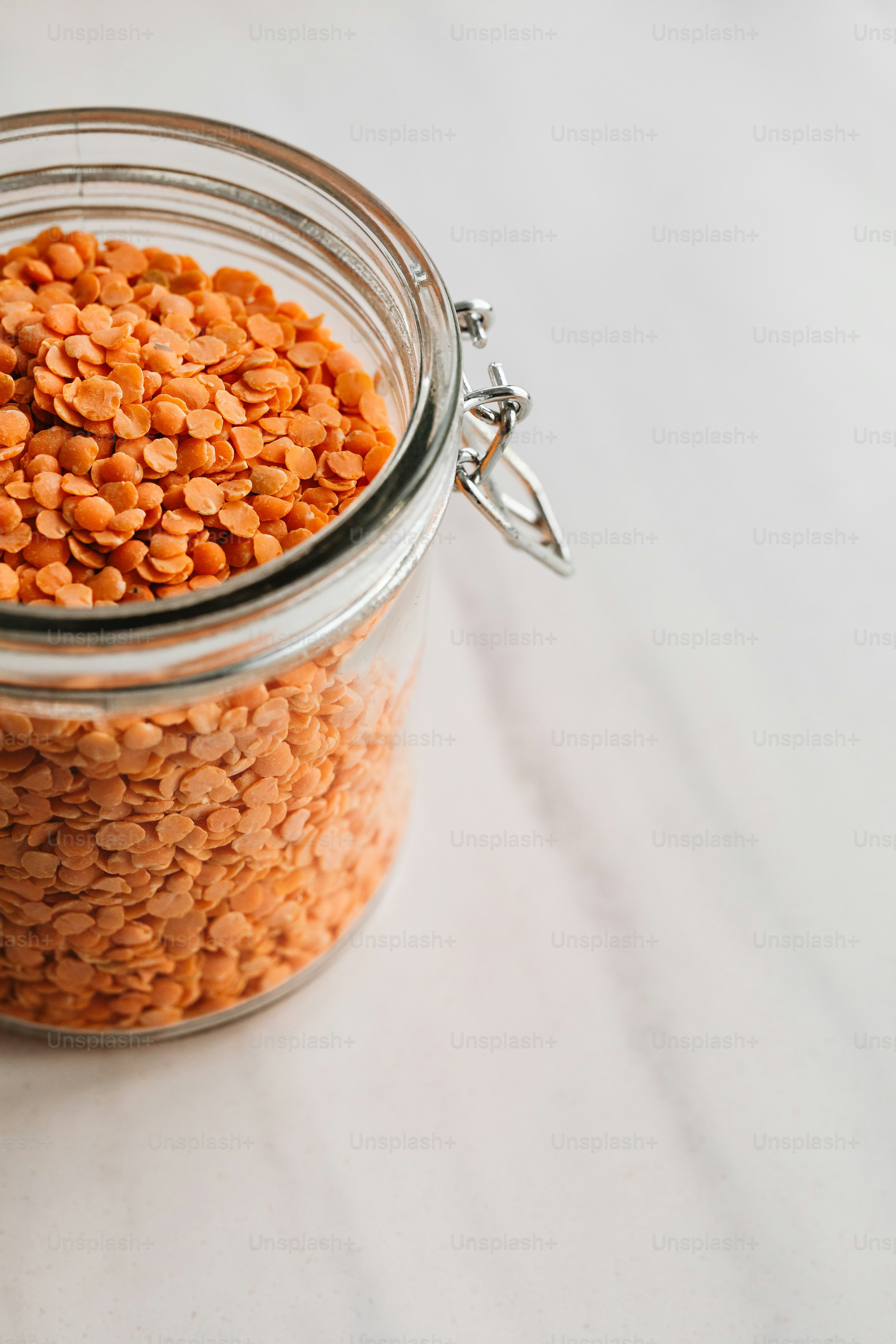 un bocal en verre rempli de lentilles corail sur une table