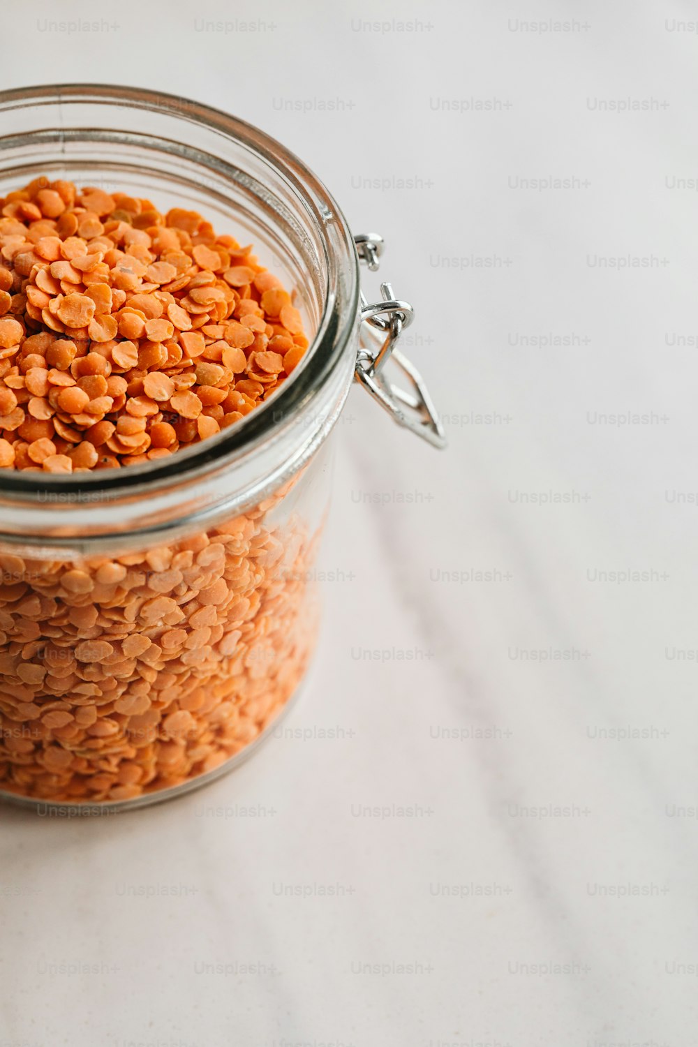 a glass jar filled with red lentils on a table