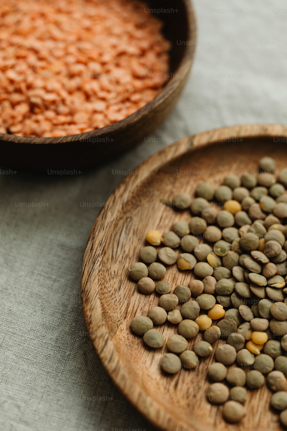 a wooden bowl filled with lentils next to a wooden bowl filled with lentils