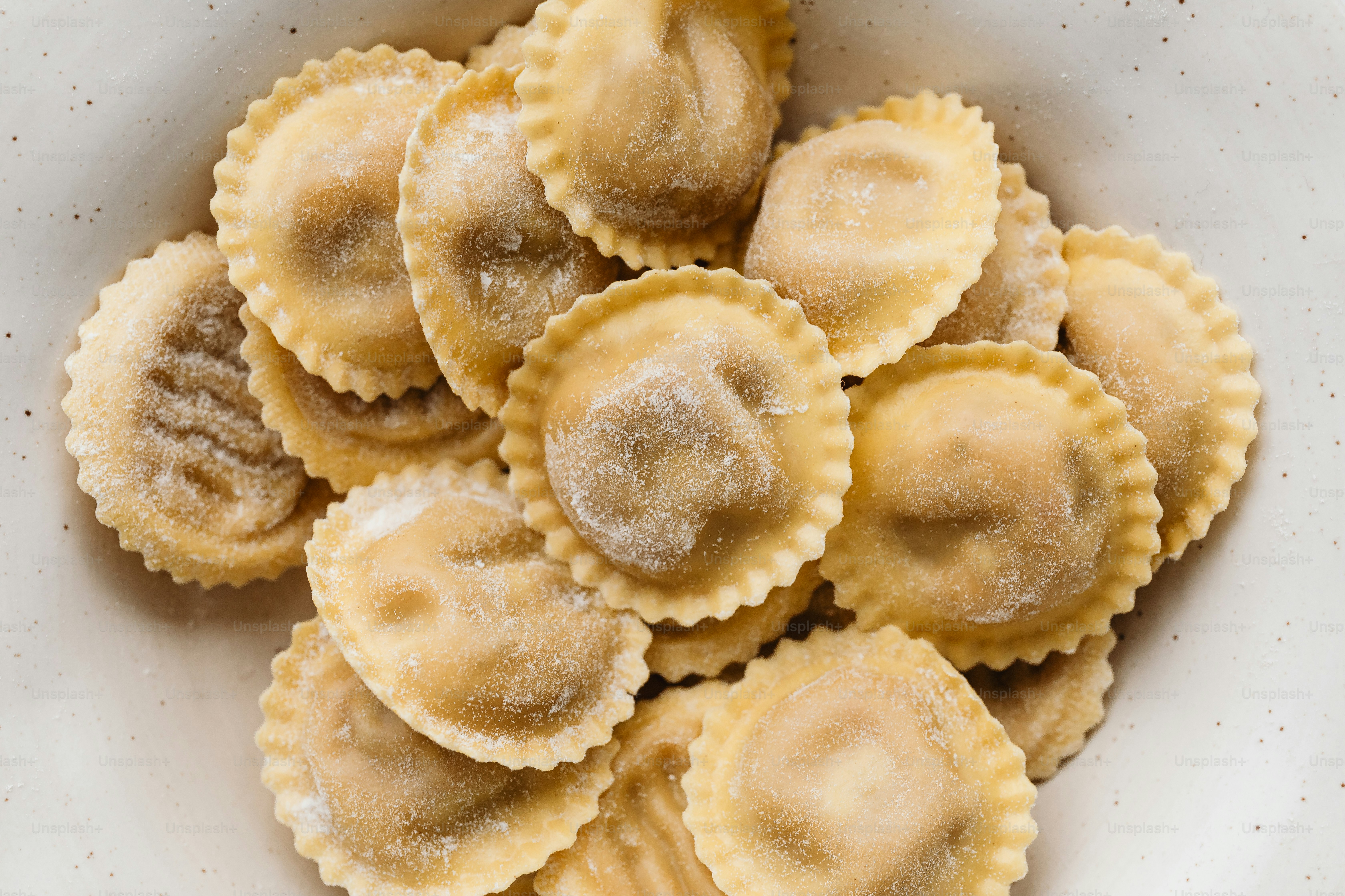 a white plate topped with ravioli covered in powdered sugar