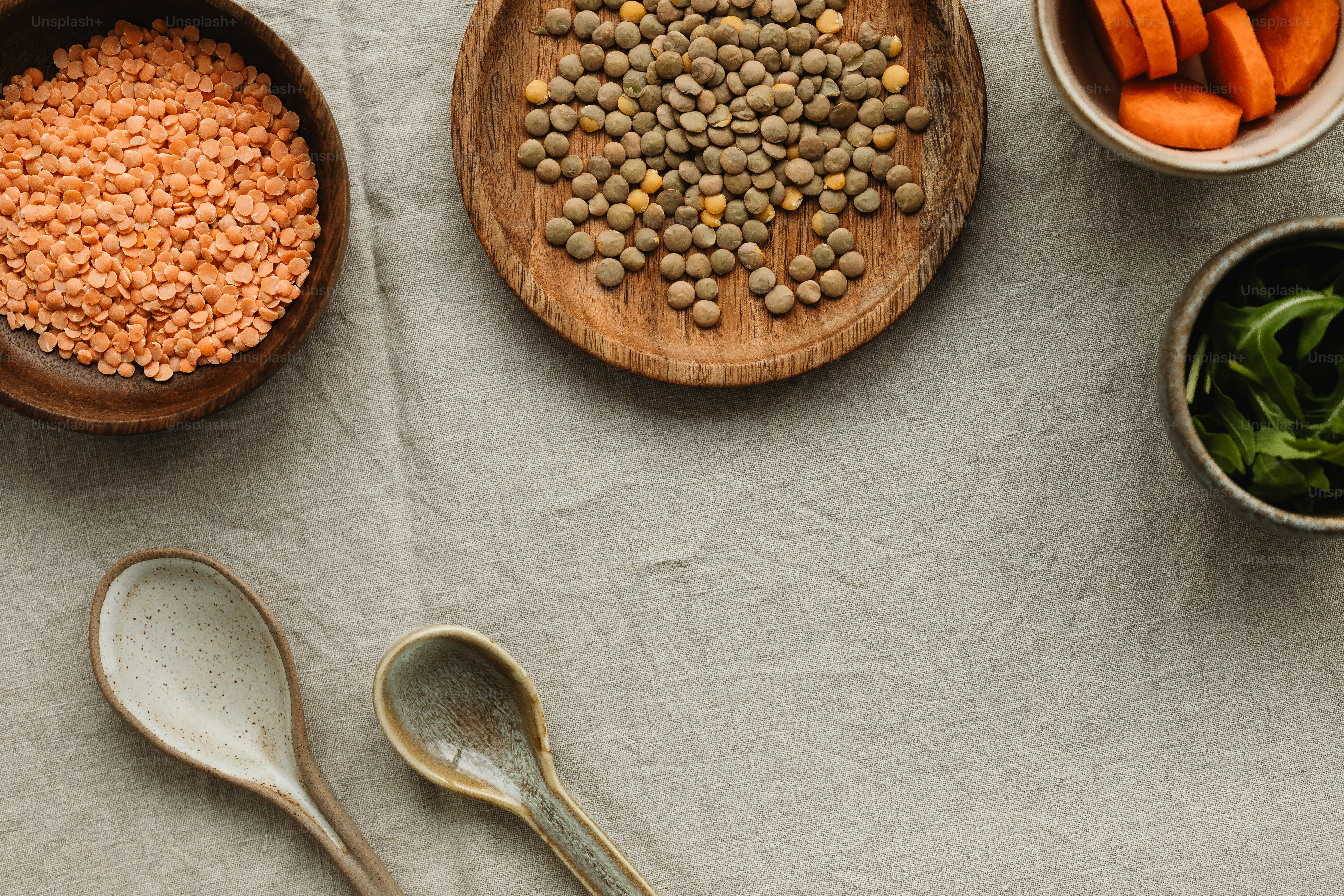 a table topped with bowls of lentils and spoons