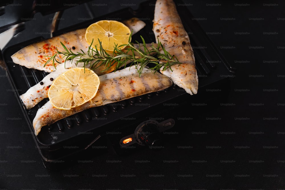 a grill with fish and lemon slices on it