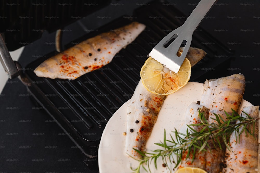 a grill with fish and lemon slices on it