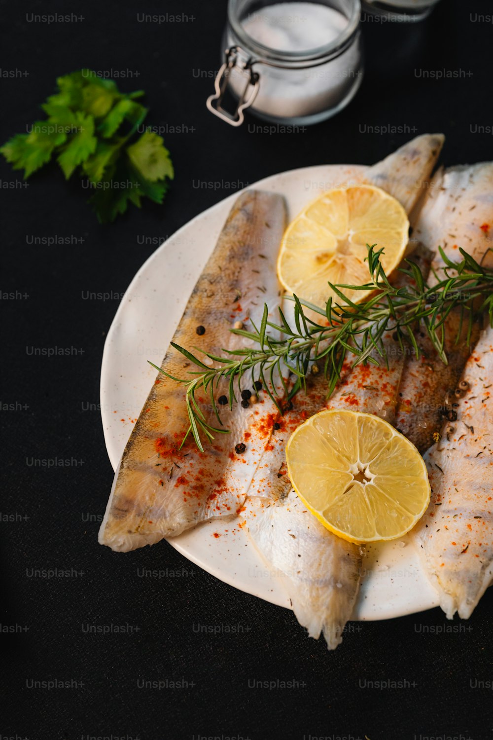 un plato blanco cubierto con pescado y rodajas de limón