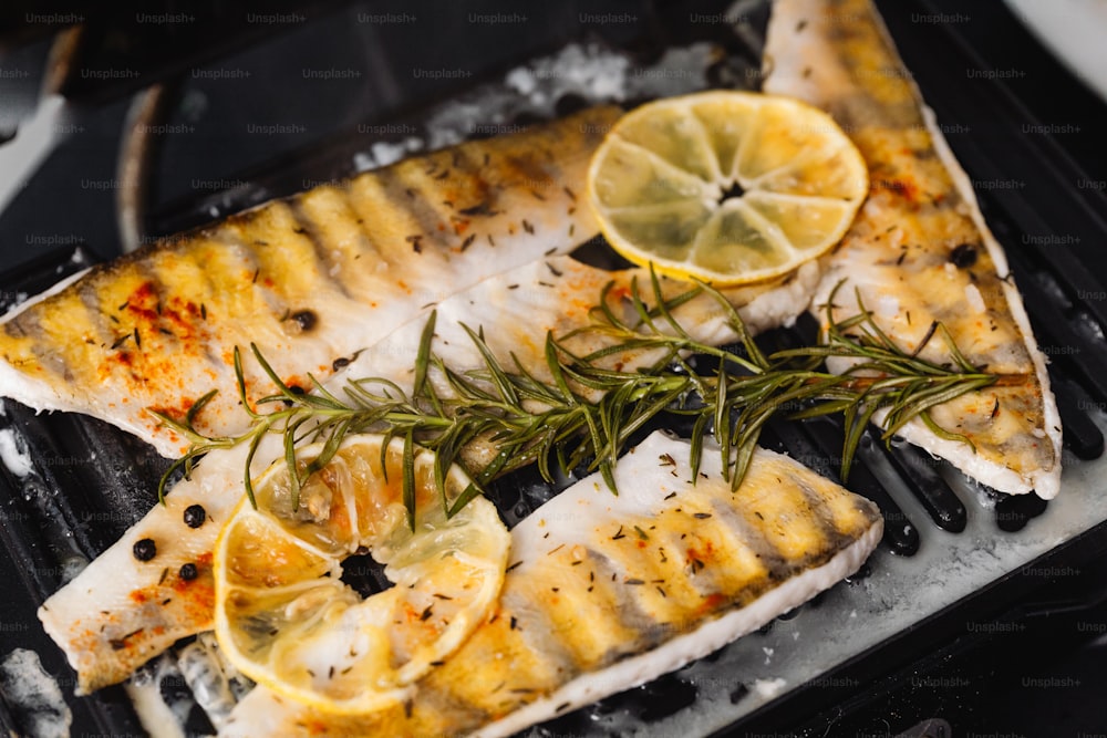 a grill with some fish and lemons on it