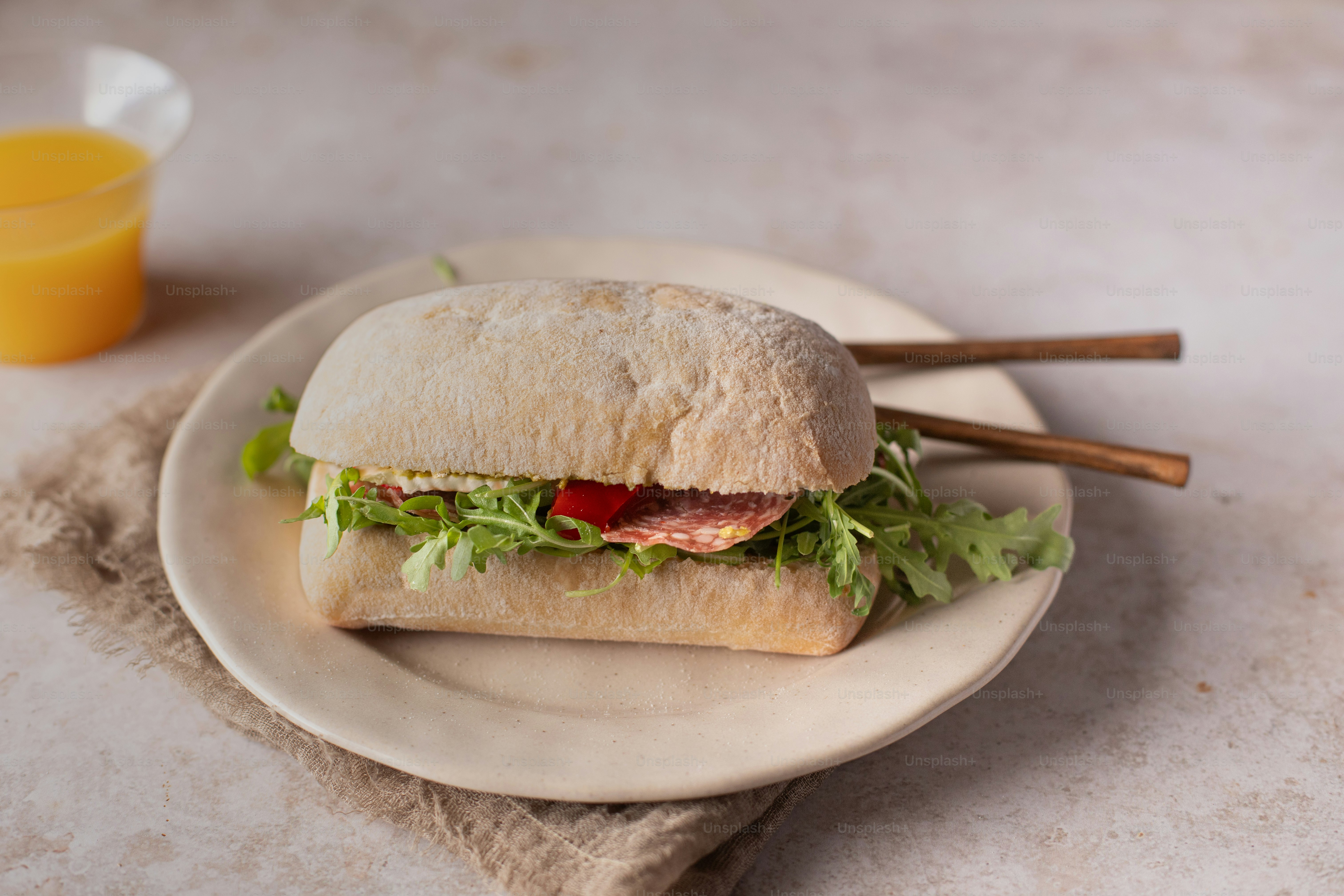 sandwich di piring di sebelah segelas jus jeruk