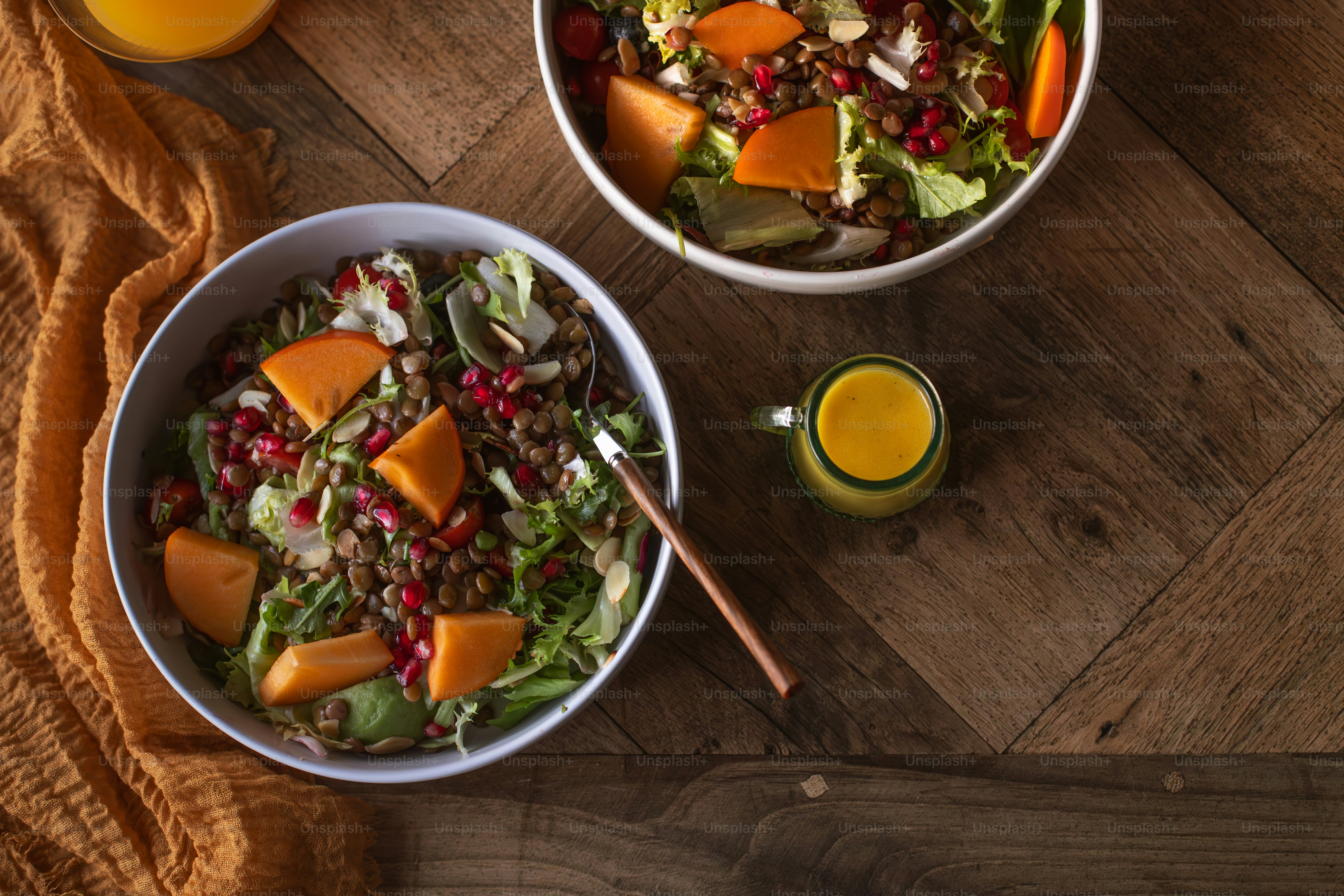 two bowls of salad and a glass of orange juice