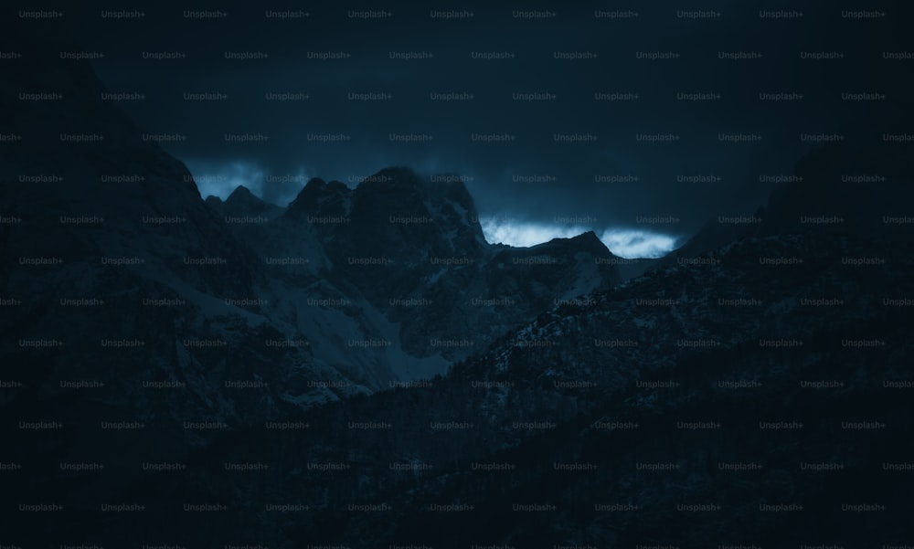 a mountain range with a dark sky in the background