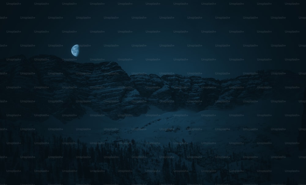 a full moon rising over a snowy mountain range