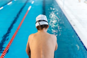 un uomo che indossa un cappello bianco in piedi accanto a una piscina