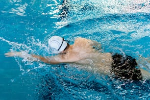 un hombre nadando en una piscina con una pelota en la cabeza