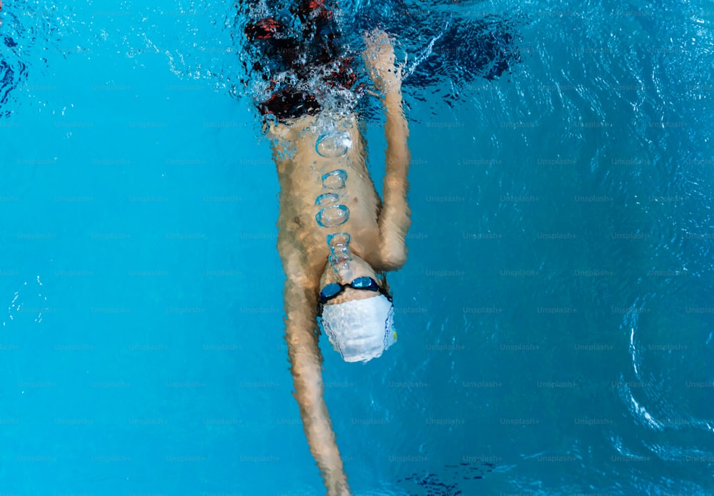 ein Mann, der mit einer Maske im Gesicht in einem Pool schwimmt