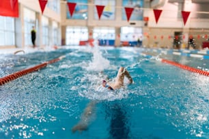 a person swimming in a pool with a red and white flag