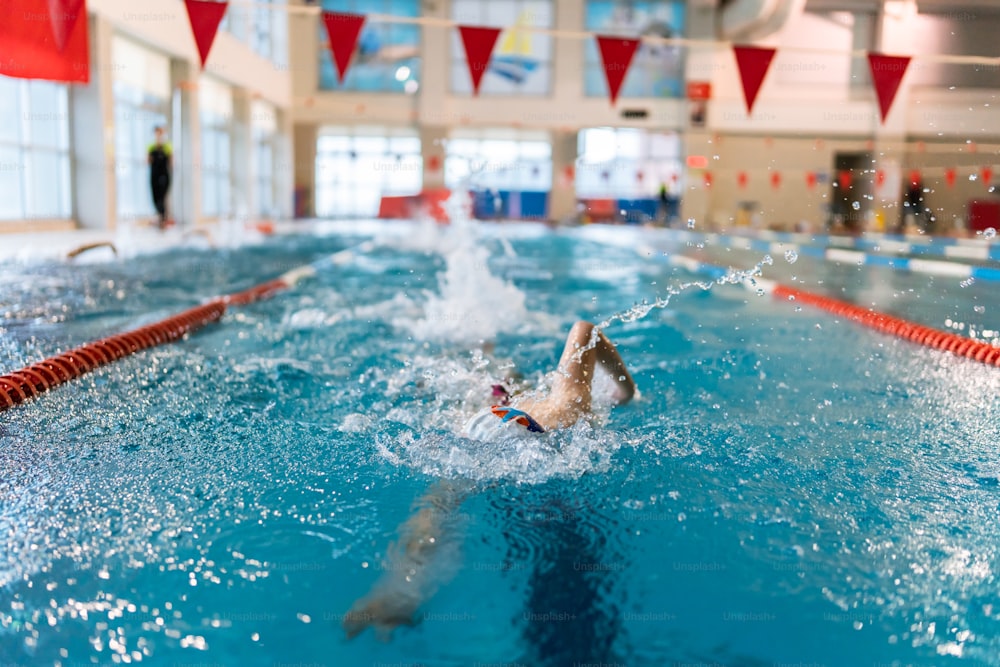 una persona nadando en una piscina con una bandera roja y blanca