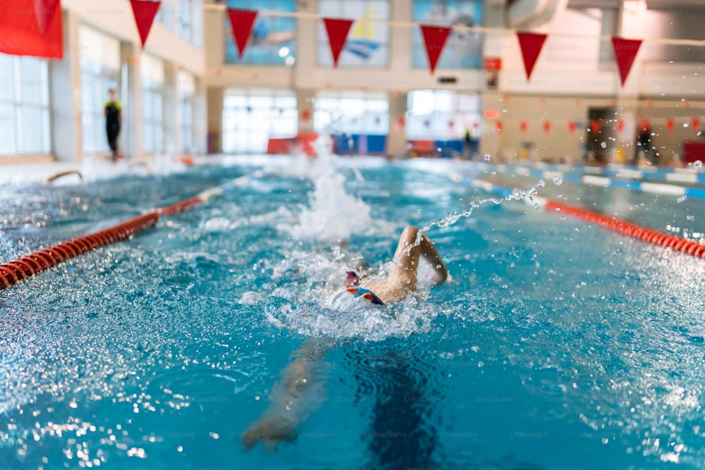 a person swimming in a pool with a red and white flag