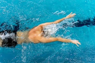 Un hombre nadando en una piscina sin camisa