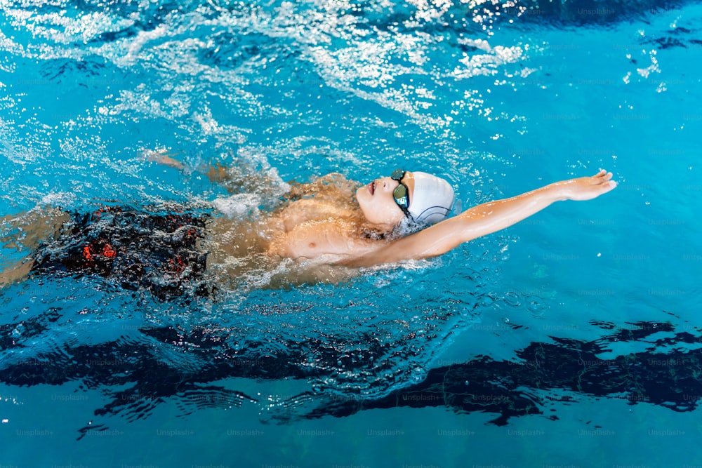 a man swimming in a pool with a hat on