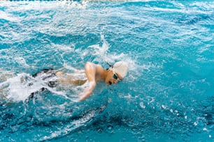 un uomo che nuota in una piscina indossando un cappello