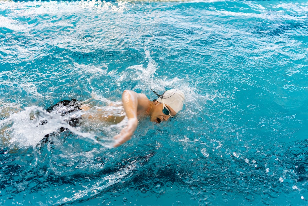 a man swimming in a pool wearing a hat