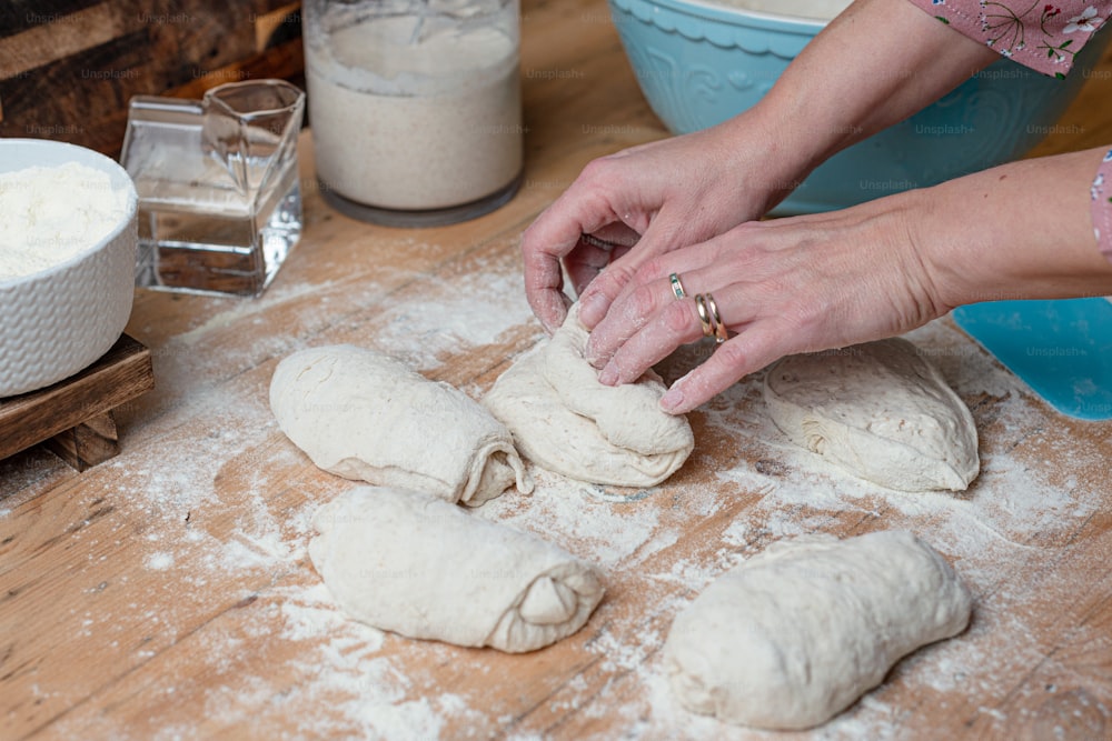 a woman kneading dough on top of a wooden table