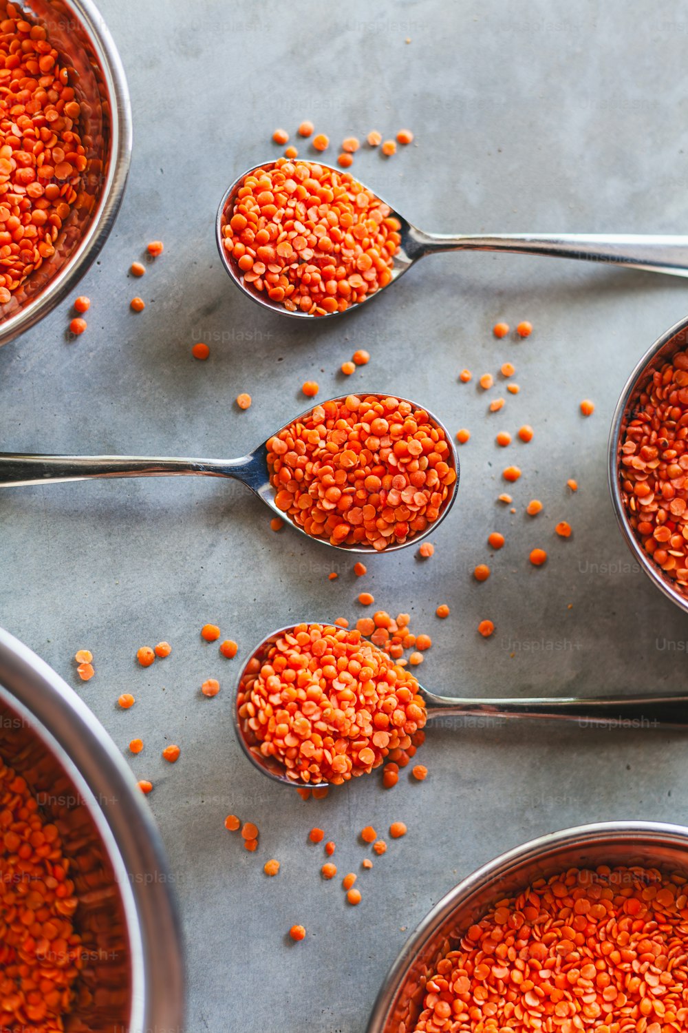 five spoons filled with red lentils on a table
