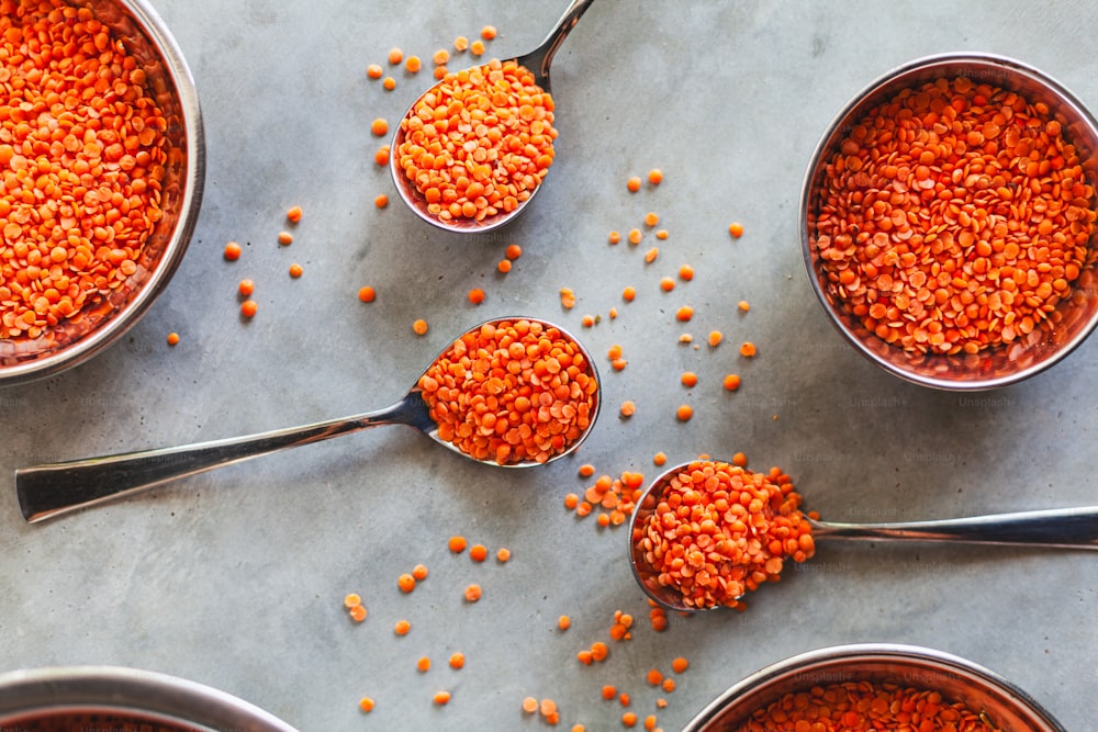 four spoons filled with red lentils on a table