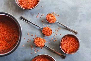 a table topped with metal measuring cups filled with red lentils