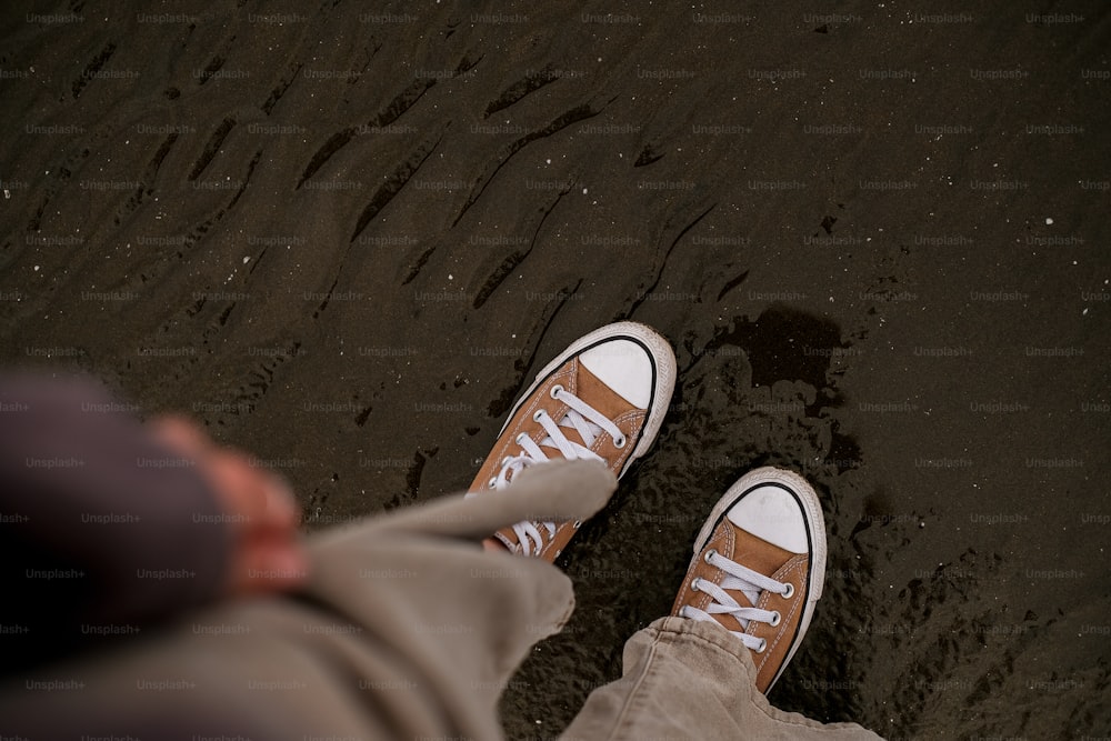una persona parada en una playa con los pies en la arena