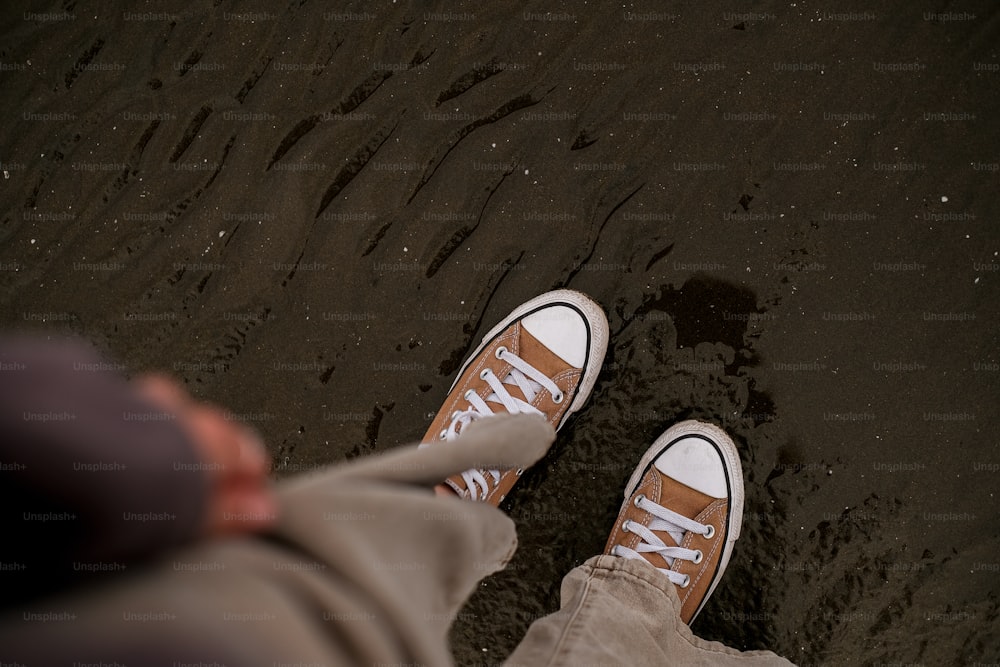 a person standing on a beach with their feet in the sand