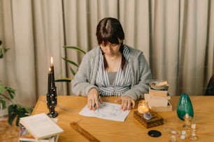 a woman sitting at a table working on a piece of paper