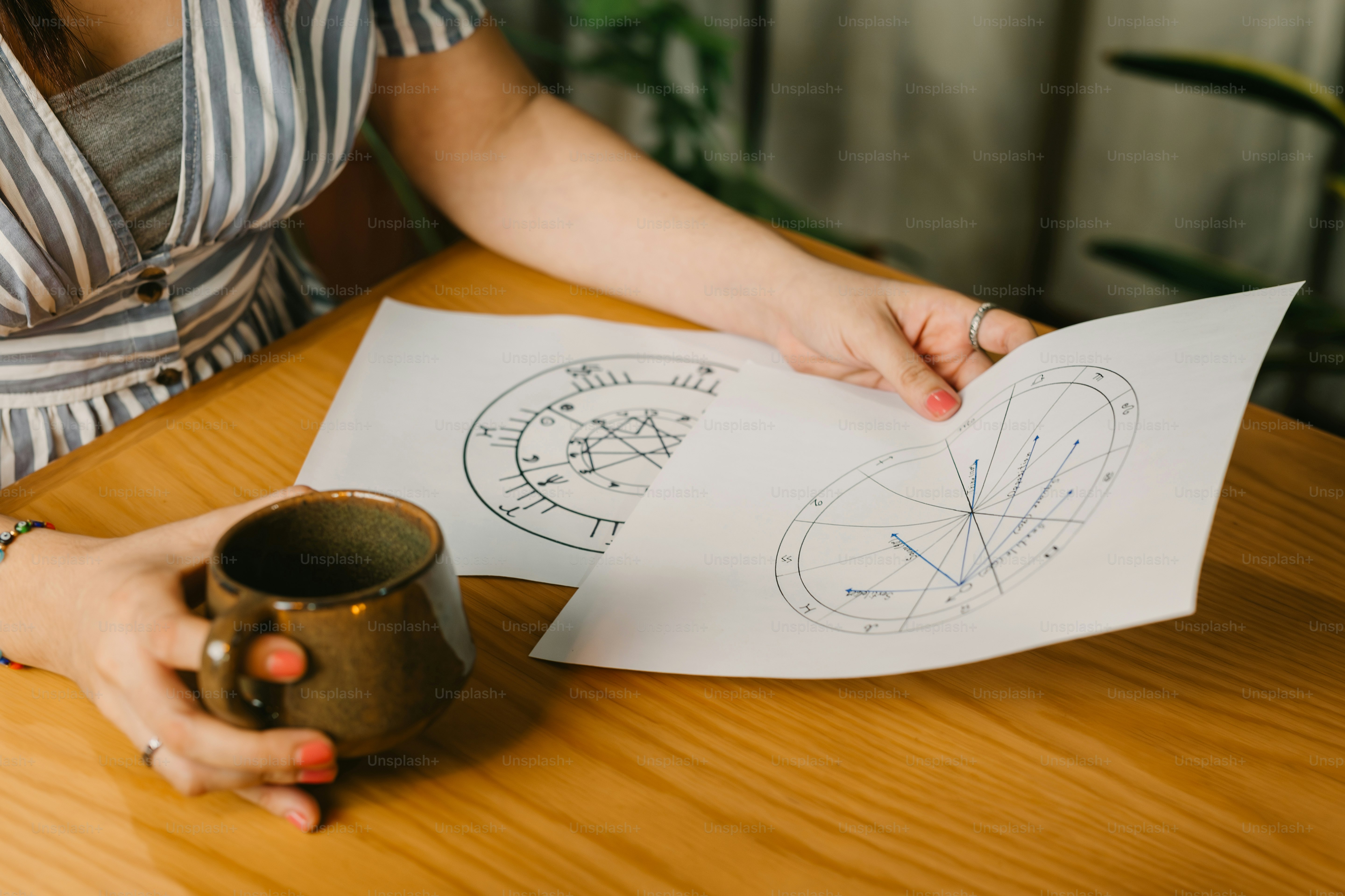 a woman sitting at a table with a cup and paper