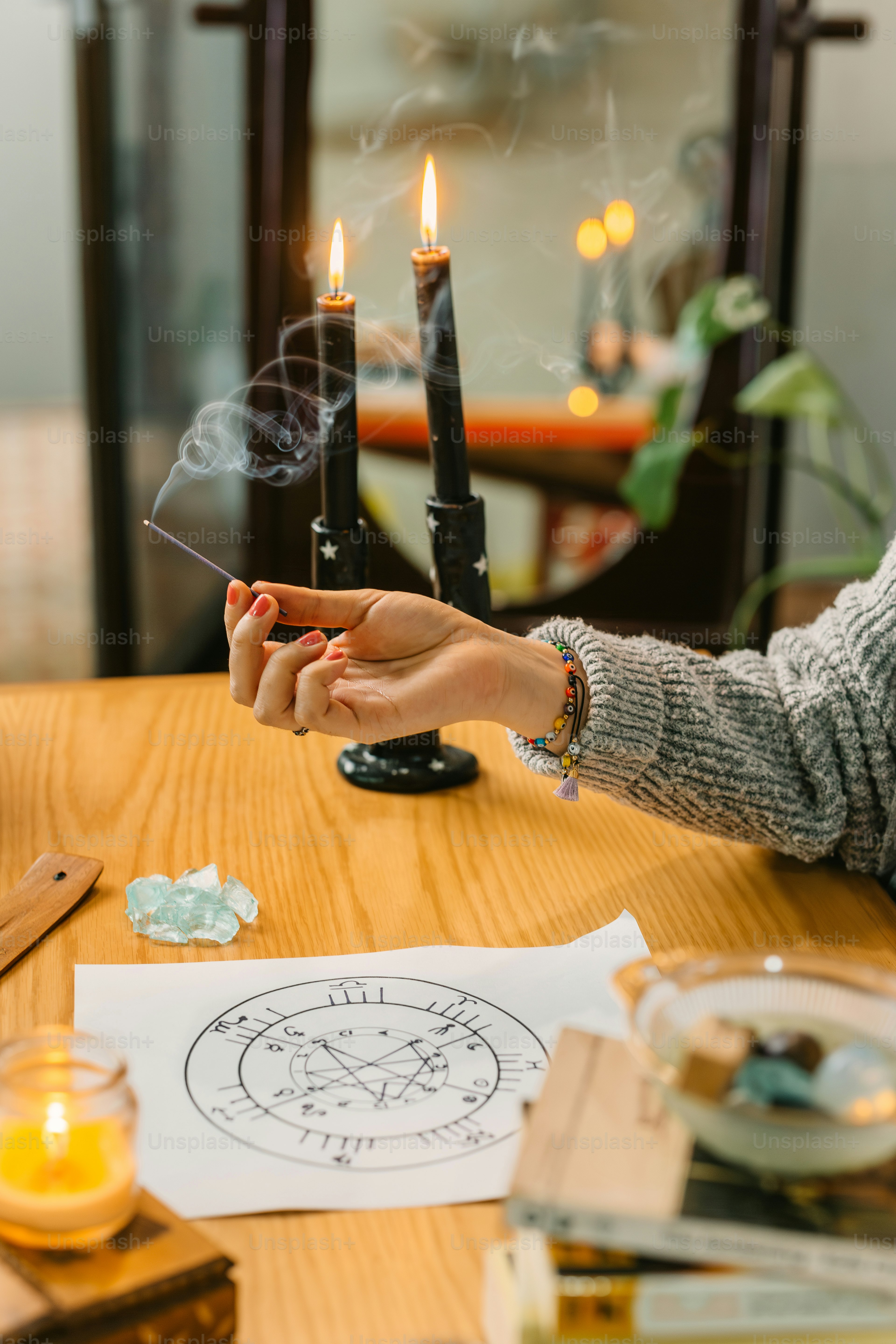 a woman sitting at a table holding a lit candle